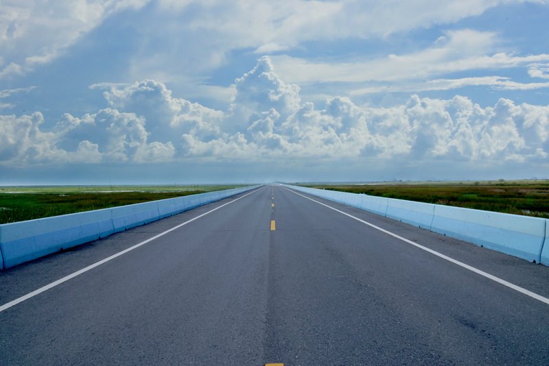 Die Ausgangssituation Leere gerade verlaufende Straße unter blau weißem Himmel.